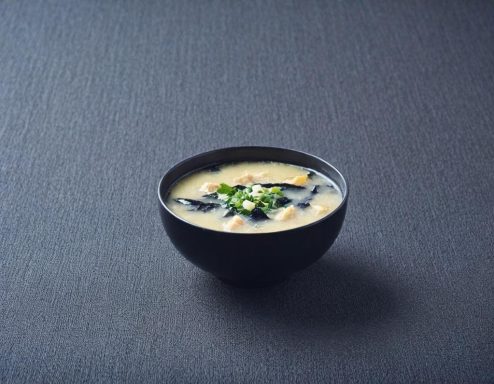 Skål med krämig misosoppa, garnerad med grönlök och alger.